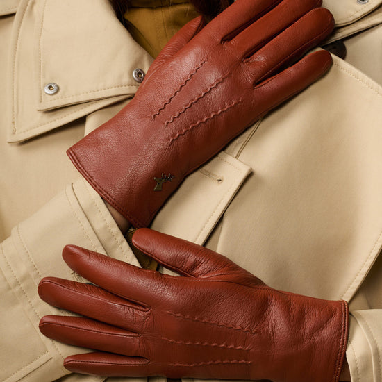 Cognac brown leather gloves laid flat with stitched seams and long cuffs