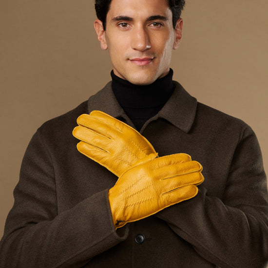 Yellow leather gloves on model, two gloves clasped at chest