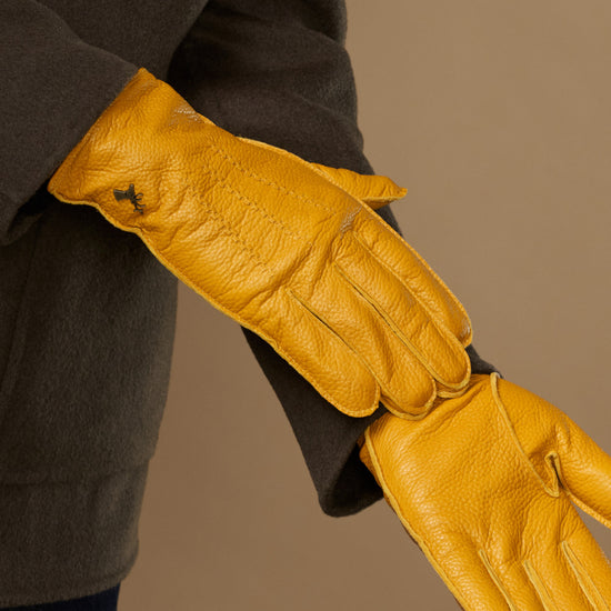 Yellow leather gloves stretched open, long cuffs and finger stitching visible