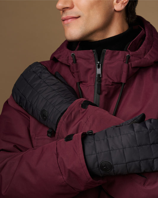 Close-up of black quilted mittens with snap details and extended cuffs.