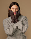Long dark brown leather gloves held together in front