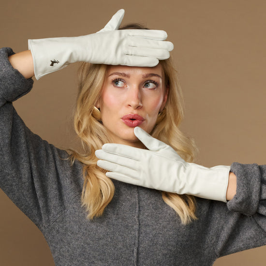 White long leather gloves held up, touchscreen fingertips visible