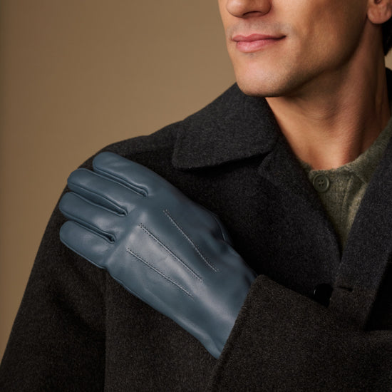 Blue sheepskin gloves worn with a dark winter coat