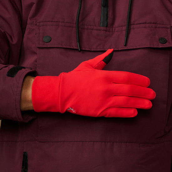 Red activity glove showing its smooth back, wrist logo and black fingertip