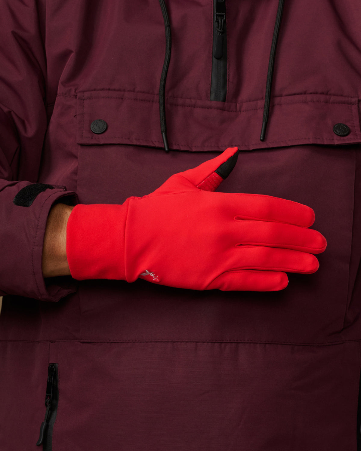 Red activity glove showing its smooth back, wrist logo and black fingertip