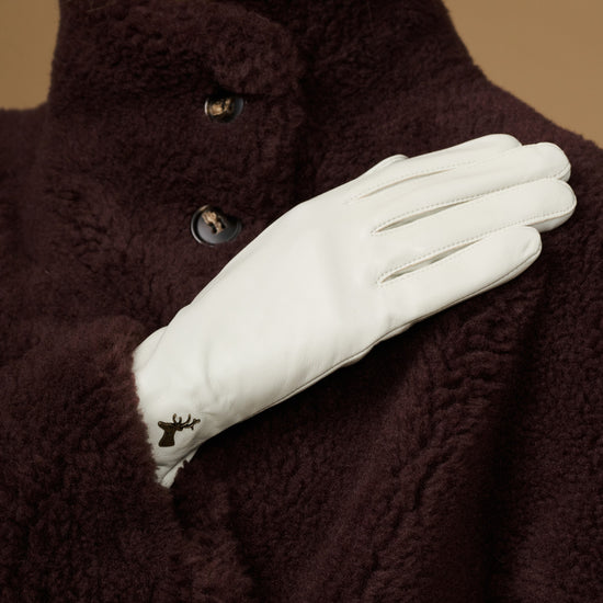 Close-up of women’s white leather gloves with stitched finger seams and tapered cuff