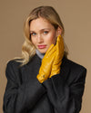 Yellow leather gloves worn with stitched knuckles and a snug wrist cuff