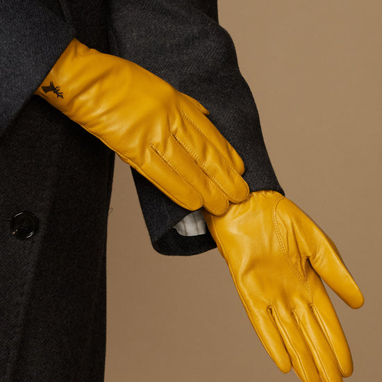Close-up of yellow leather gloves showing stitched seams and shaped fingertips