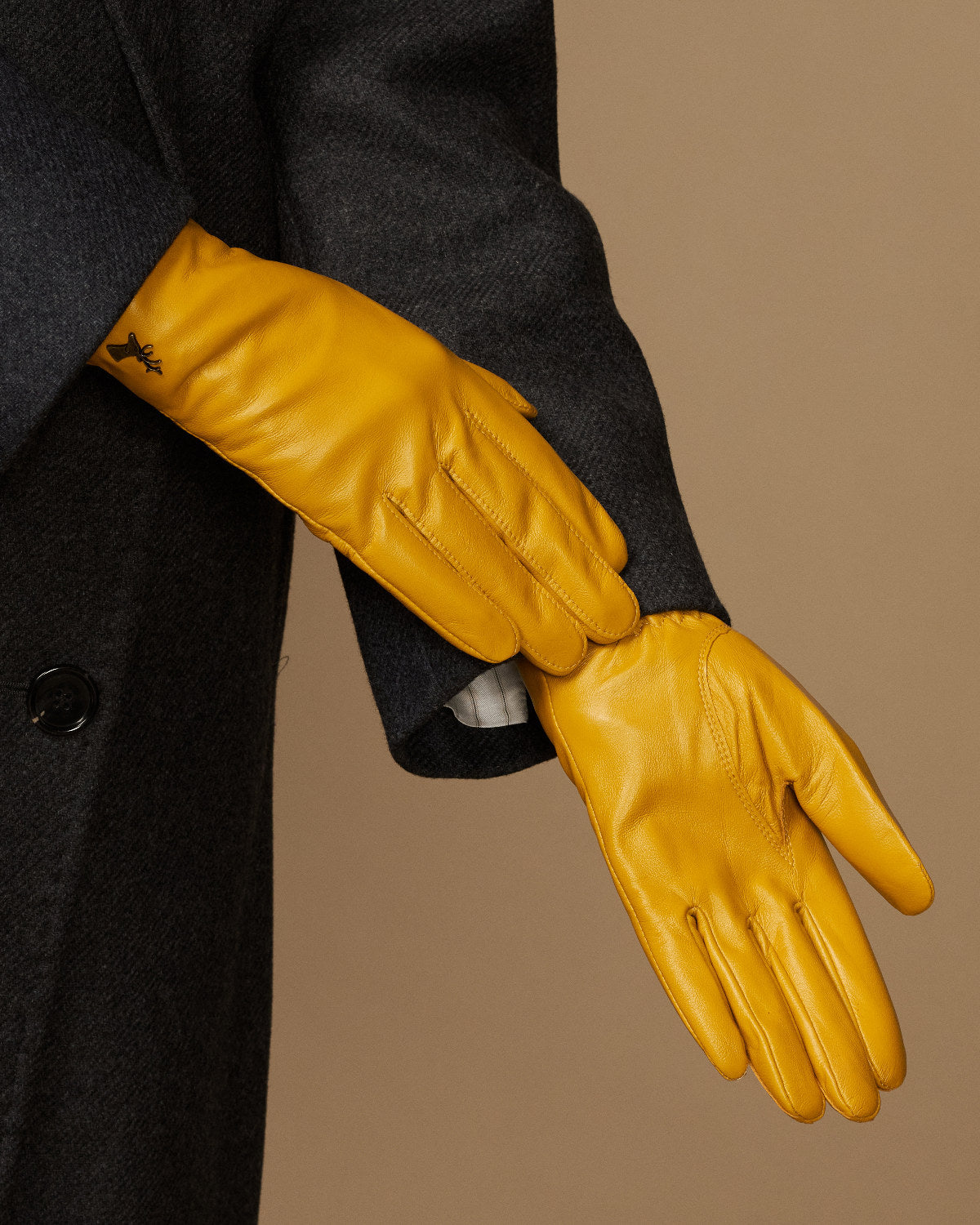 Close-up of yellow leather gloves showing stitched seams and shaped fingertips