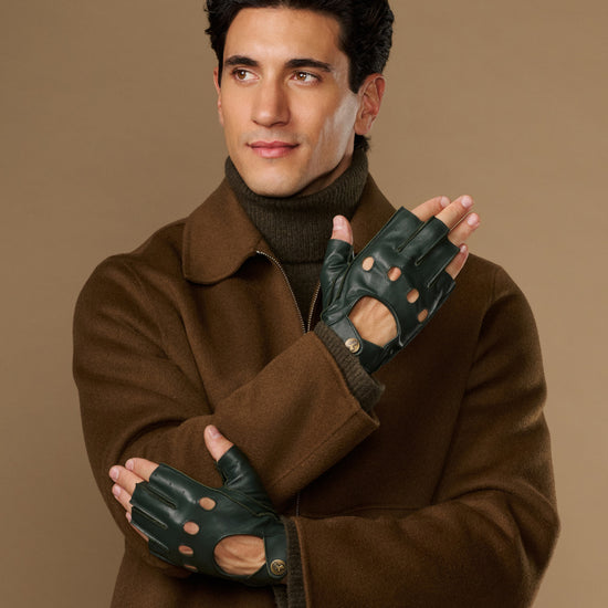 Dark green fingerless driving gloves with perforated knuckles and wrist openings, worn on both hands
