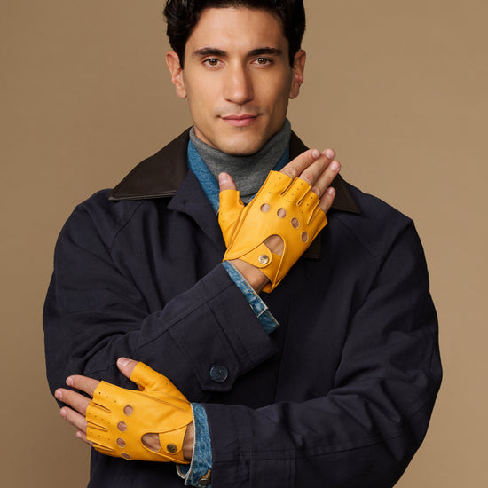 Yellow fingerless driving gloves with perforated panels, palm-forward hand pose