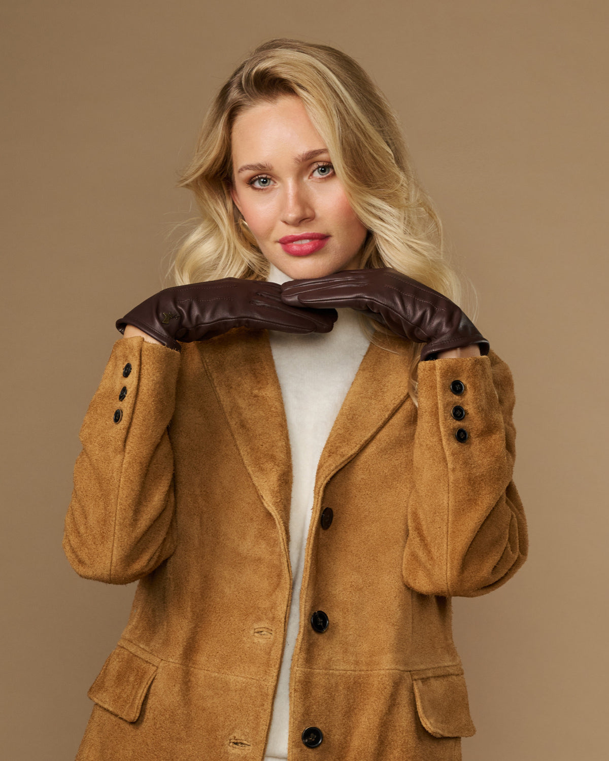 Brown fleece-lined leather gloves held up near coat hood, cuffs visible