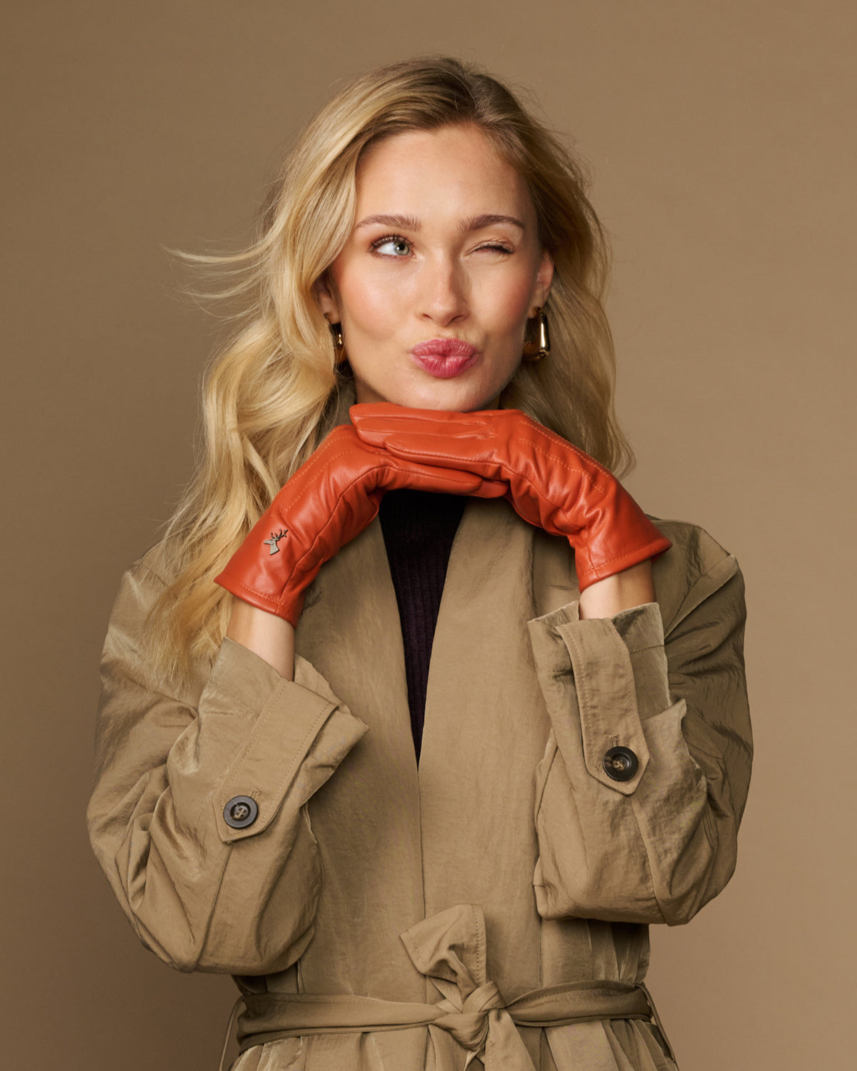 Orange sheepskin leather gloves with fleece lining, worn with arms crossed at chest