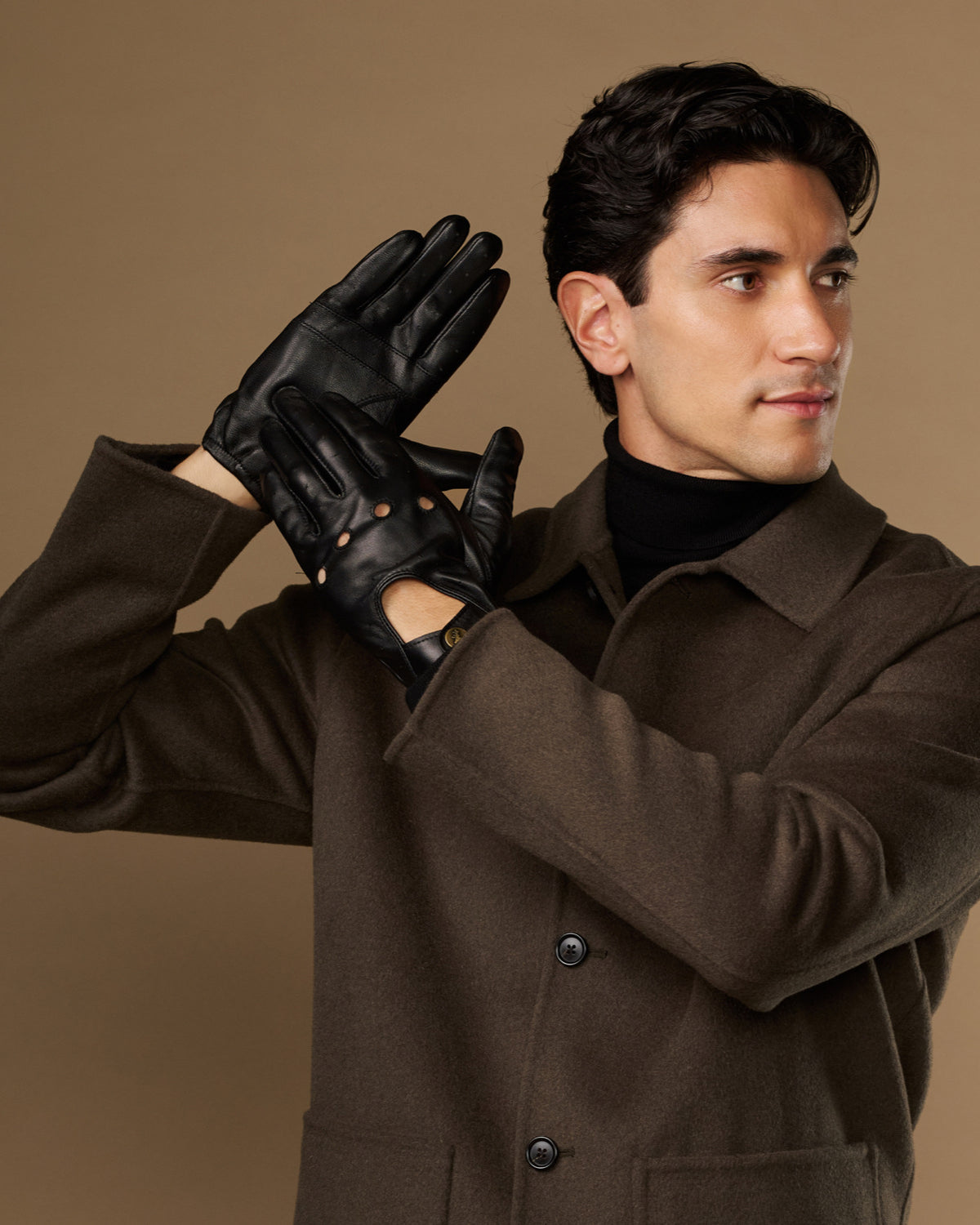 Pair of black driving gloves showing stud accents and elastic wrist fit