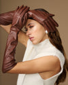 Pair of women’s brown leather elbow gloves, hands posed with finger seams visible.