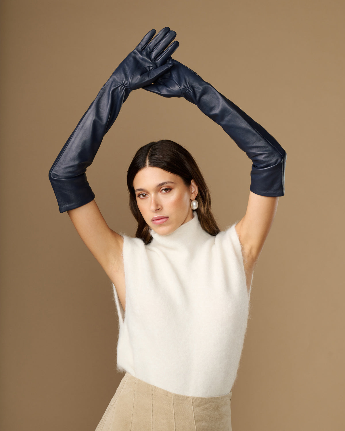 Navy leather opera gloves with long cuffs and silk lining, hands raised overhead