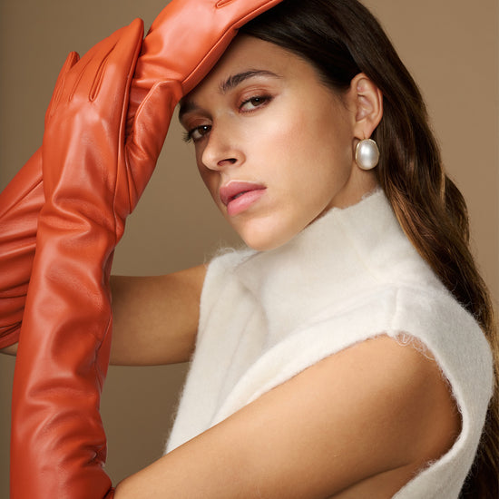 Close-up of orange leather elbow glove covering the raised hand and wrist