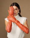 Pair of orange leather elbow gloves with smooth finish and curved finger seams