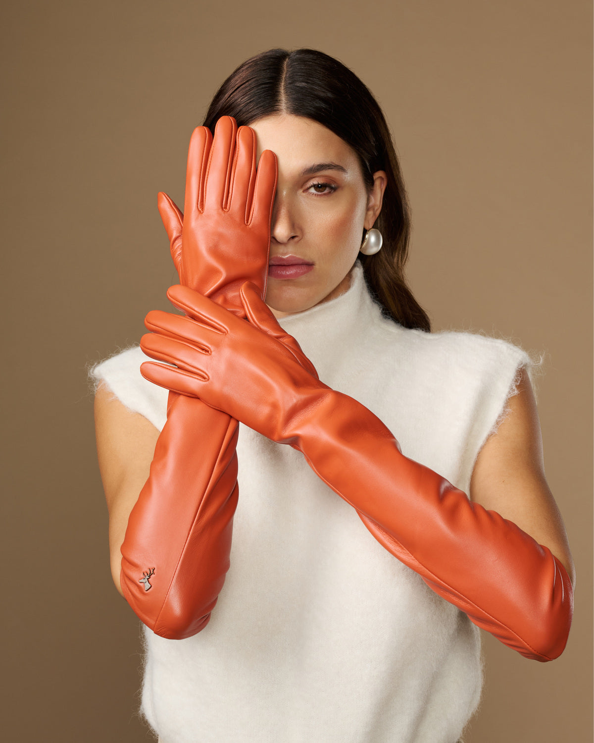 Pair of orange leather elbow gloves with smooth finish and curved finger seams