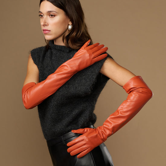 Orange lambskin leather gloves with silk lining and touchscreen tips, hands crossed
