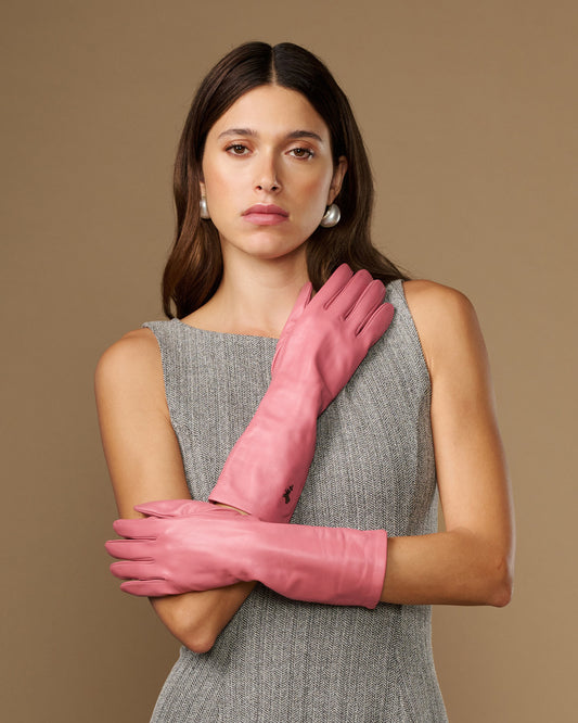 Pink mid-forearm leather gloves, smooth finish, pair folded with hands crossed