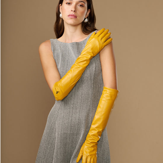 Yellow leather elbow-length gloves with smooth finish and pointed logo on wrist