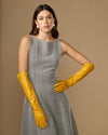 Yellow leather elbow gloves with long cuffs and finger shaping, worn with dress