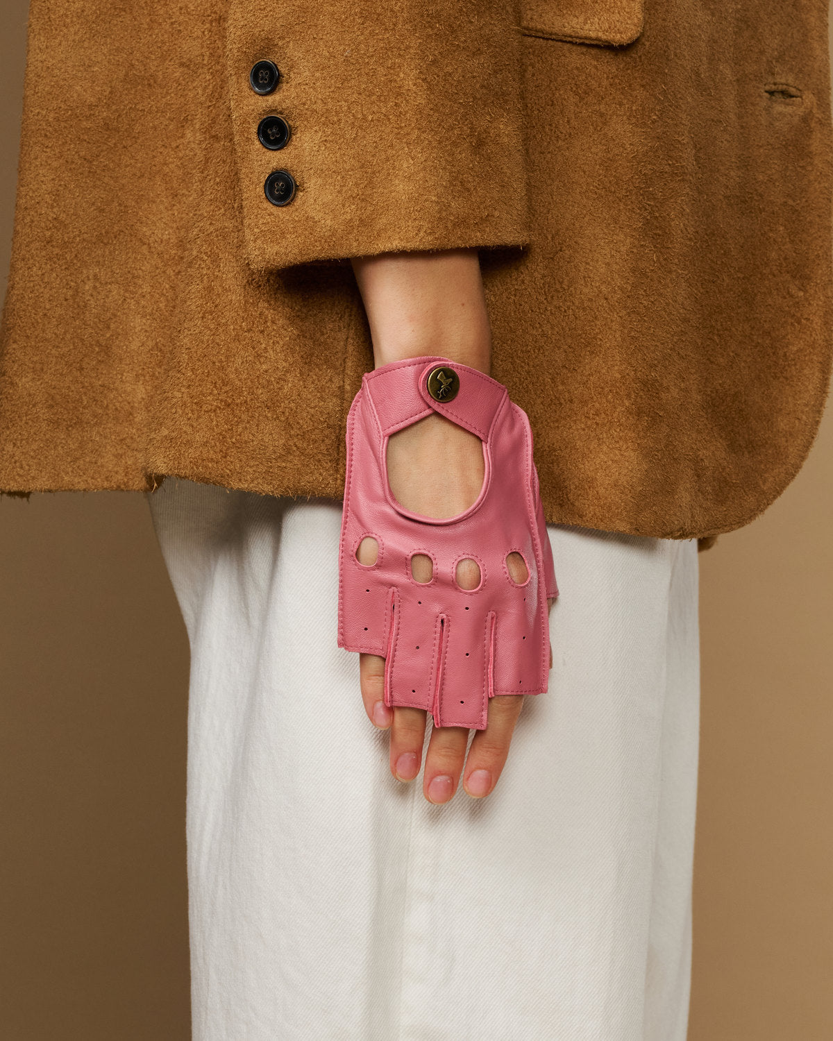 Pink fingerless driving gloves shown from front with snap strap and button accents