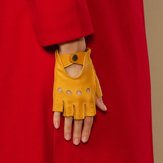 Yellow fingerless lambskin glove with thumb opening, snap cuff, and perforation panels