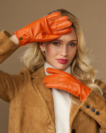 Orange leather deerskin gloves with stitched fingers and soft cuff lining, worn on hands