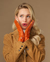 Orange leather gloves with stitched fingers and soft lined cuffs, hands held at neck