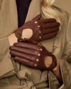 Brown leather gloves with perforated finger panels and decorative button accents
